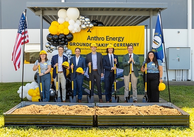 Officials holding gold shovels at Anthro Energy's groundbreaking ceremony in Louisville, Kentucky, in front of a company banner flanked by US and Kentucky flags