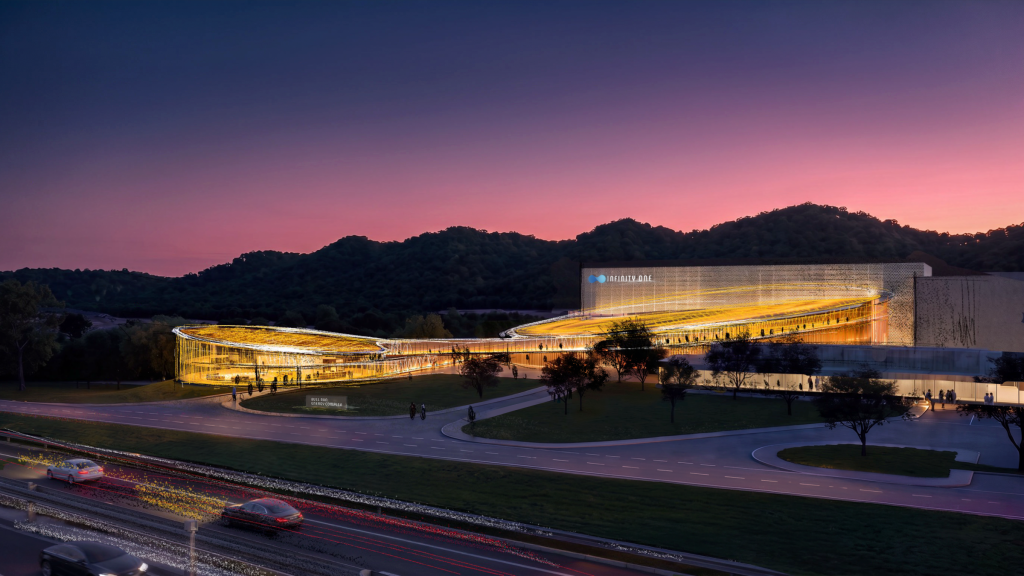 Architectural rendering at dusk of a long, curved, lit glass building labeled Infinity One beside a landscaped drive and a highway with passing cars, wooded hills behind
