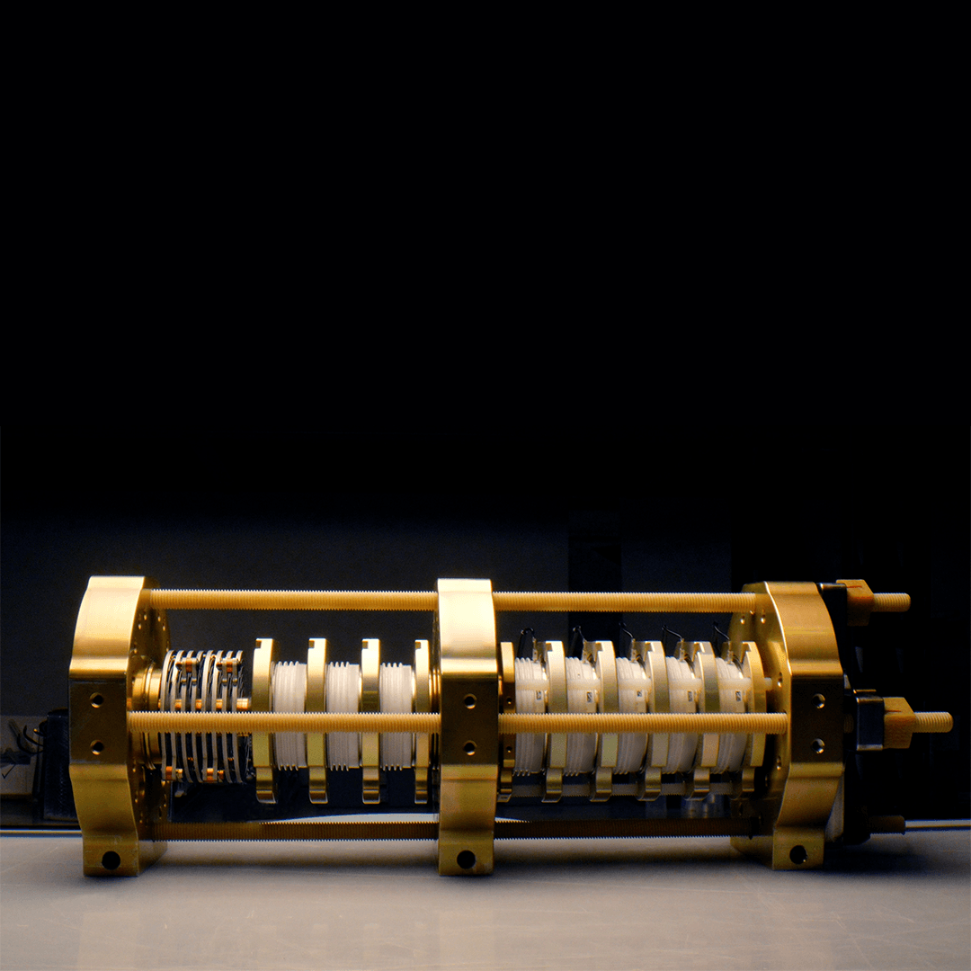 Rows of white disc-shaped components and metal spacers held between three gold-colored plates on threaded rods, sitting on a white bench against a dark background.