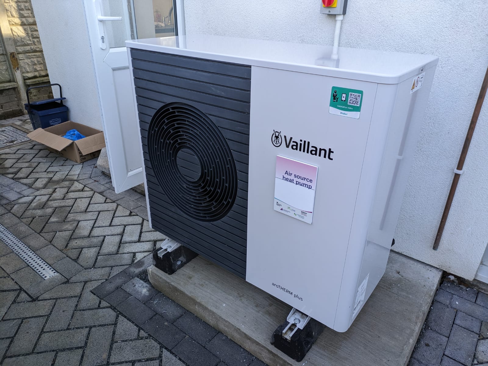 An air-source heat pump unit installed on the exterior wall of a terraced house