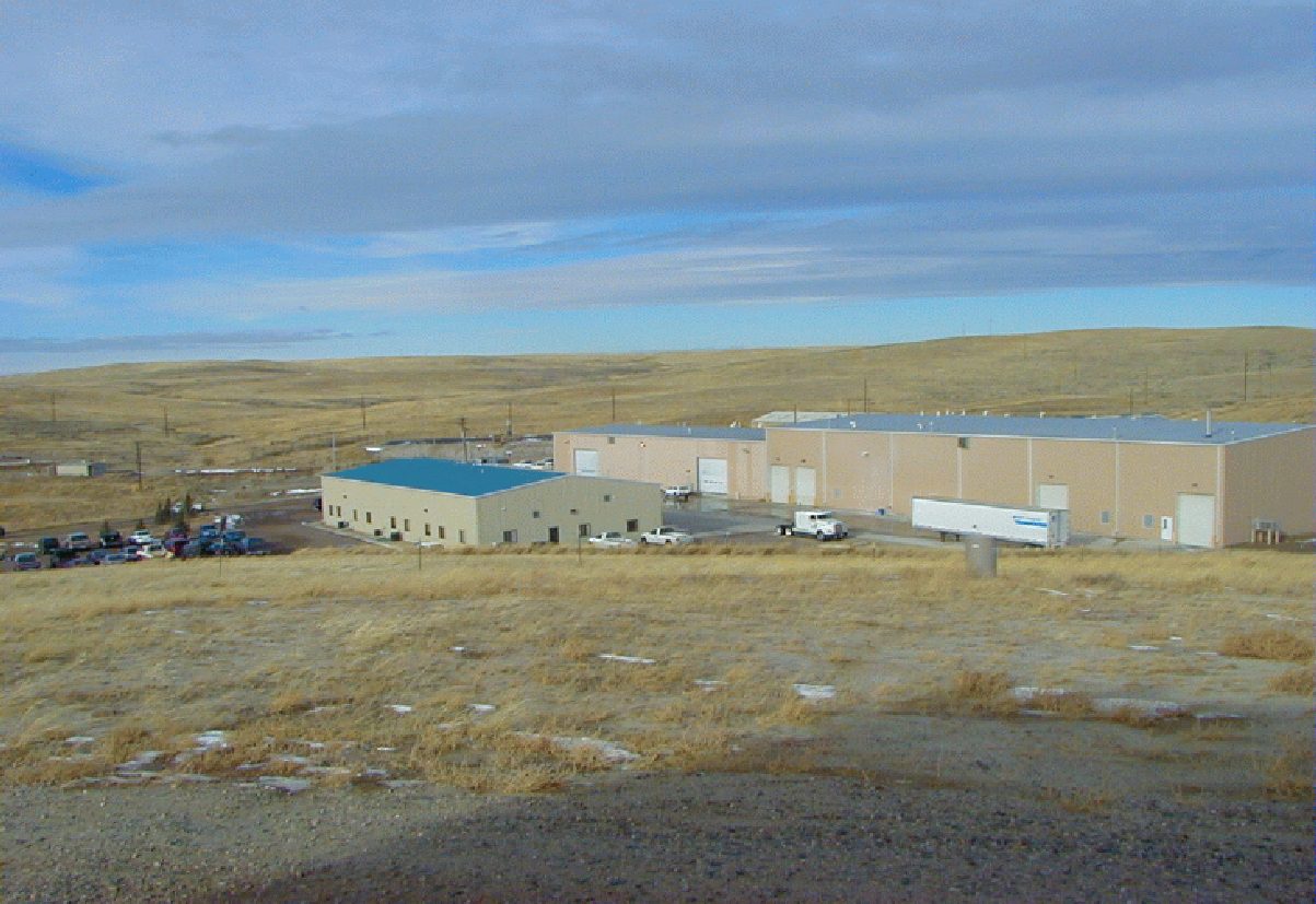 Central processing plant buildings at a uranium in-situ recovery site on open prairie, with a parking lot and a trailer at the loading dock