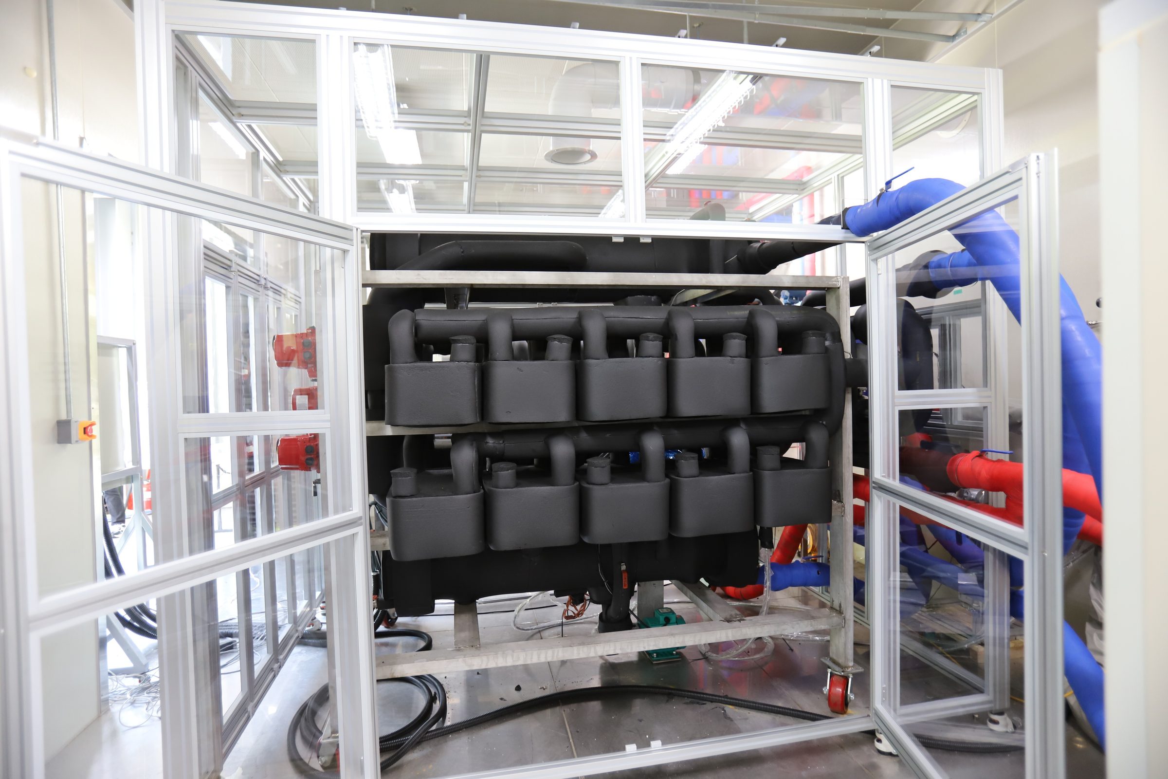 The 10 kW-class chemical adsorption heat pump prototype, wrapped in black insulation, on a test stand inside an enclosure at KIMM