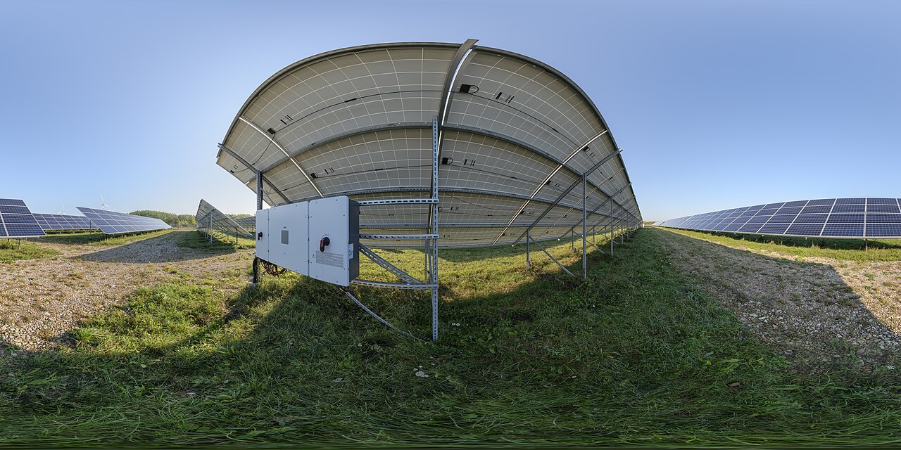 Utility-scale solar inverter cabinets mounted beside photovoltaic panel racks at a solar park